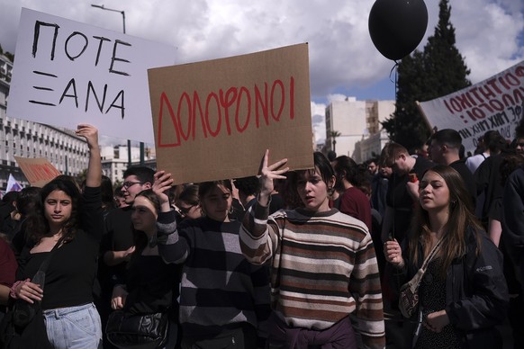 05.03.2023, Griechenland, Athen: Menschen halten Plakate hoch, auf denen in griechisch die Worte «Mörder» (M-l) und «Nie wieder!» stehen, bei einer Demonstration vor dem Parlament. Immer neue Details  ...