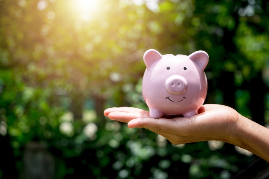 Woman hand holding piggy bank with sunrise, saving, charity, fundrasing community care, superannuation, financial crisis concept