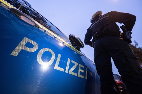 ARCHIV - 30.11.2023, Baden-Württemberg, Stuttgart: Eine Polizistin steht im Rahmen eines Fototermins neben einem Polizeifahrzeug (gestellte Szene). Wegen des Verdachts der Mitgliedschaft in einer ausl ...