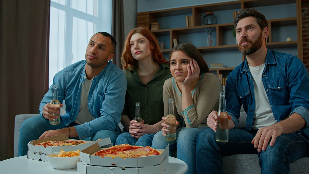 Multiethnic friends watch television with beer pizza diverse men women supporters watching TV sport game football match soccer multiracial fans worried sad disappointed by failure team losing no goal. ...