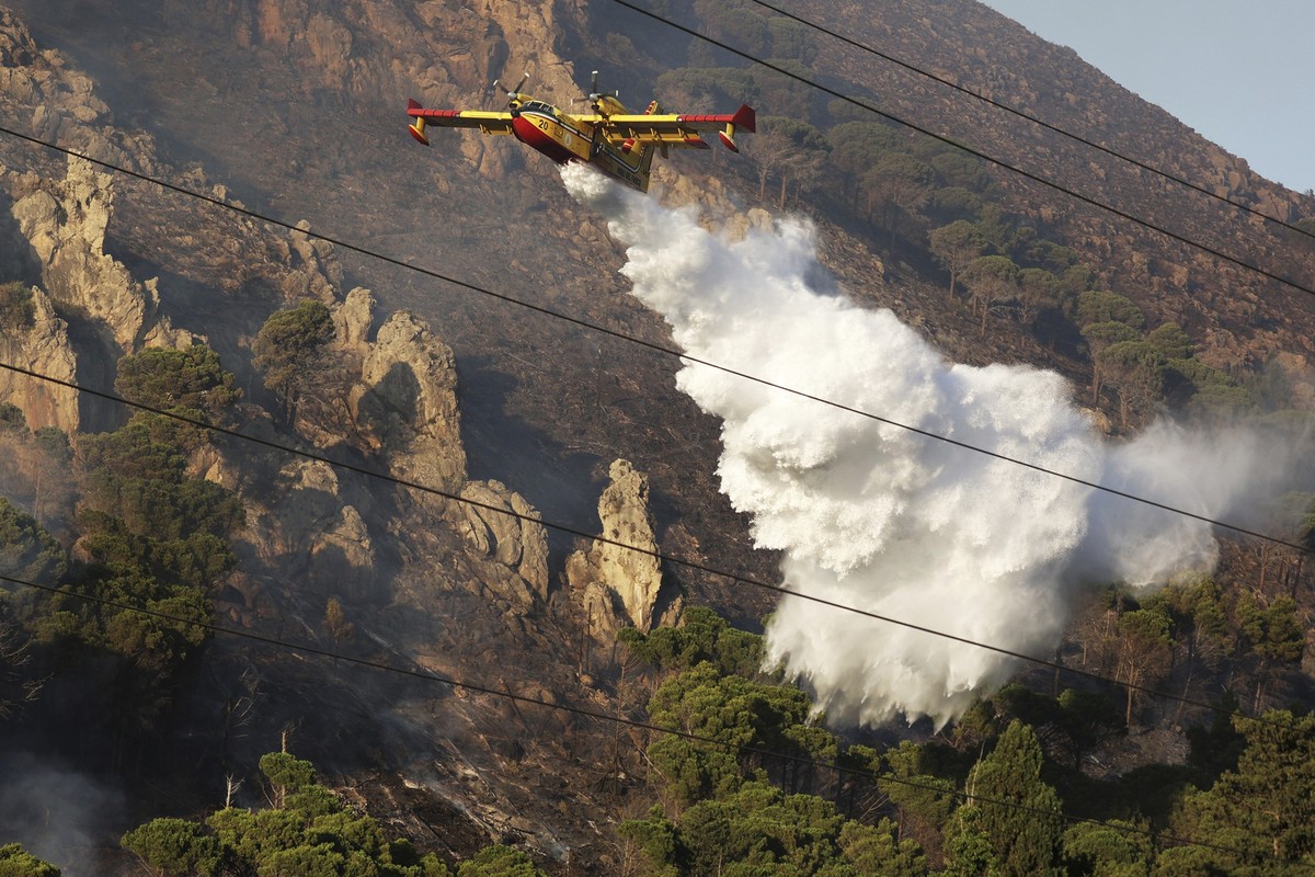 ARCHIV - 26.07.2023, Italien, Altofonte: Ein Löschflugzeug wirft Wasser über einem Waldbrand auf einem Berg in Sizilien ab. (zu dpa: «Waldbrand in Süditalien: Feriendorf evakuiert») Foto: Alberto Lo B ...