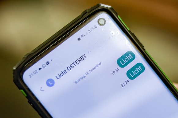 PRODUKTION - 19.12.2022, Schleswig-Holstein, Osterby: Mit einem Smartphone ist die Nachricht &quot;Licht&quot; an einen SMS-Service geschickt worden. Das Dorf spart Strom mit einer außergewöhnlichen & ...