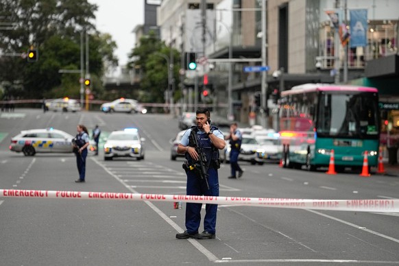 20.07.2023, Neuseeland, Auckland: Bewaffnete neuseeländische Polizeibeamte stehen an einer Straßensperre im zentralen Geschäftsviertel, nachdem Schüsse gefallen waren. Ein Bewaffneter im neuseeländisc ...