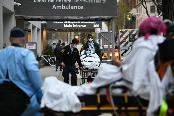 April 10, 2020, New York, New York, United States: A man is wheeled out of Lenox Hill Hospital in Manhattan as a woman, foreground, is wheeled into the emergency room on Friday, as the daily death tol ...