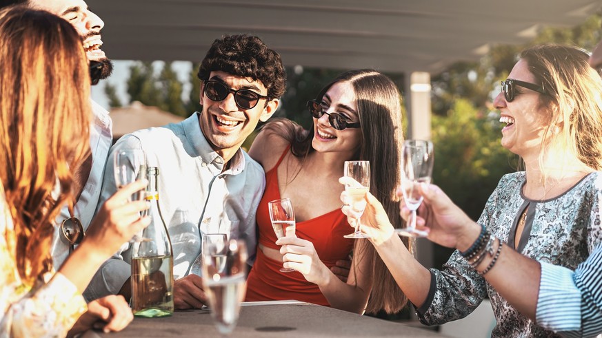 Happy friends with sunglasses cheering and drinking champagne at garden party outdoor - Young millennials people having fun at weekend afternoon - Youth lifestyle and nightlife concept