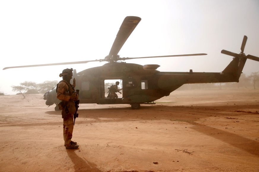 FILE PHOTO: A French soldier stands guards in front of an NH90 Caiman military helicopter during Operation Barkhane in Ndaki, Mali, July 29, 2019. Picture taken July 29, 2019. REUTERS/Benoit Tessier/F ...