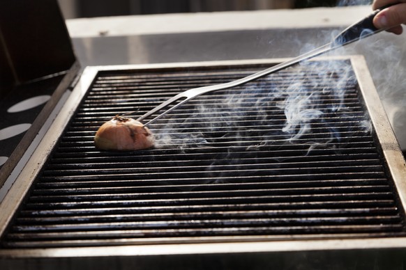 Getting the grill ready for some cooking - rubbing halved onion on the hot grate.