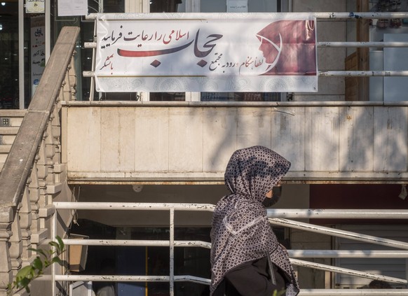 Iran, application du hijab Une Iranienne passe devant une pancarte indiquant « Veuillez observer le hijab islamique en entrant dans le complexe, devant l'entrée principale d'un centre commercial du centre-ville de Téhéran, avril ...