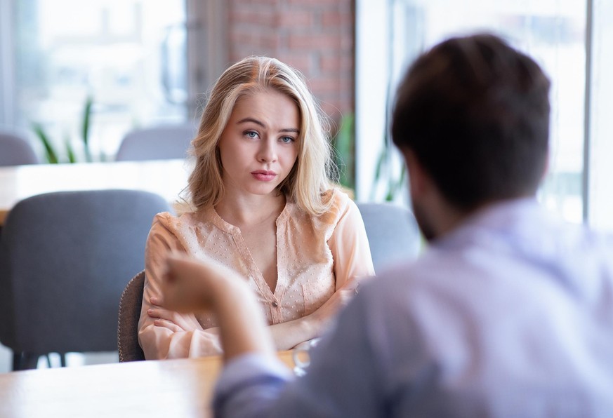 Bad date. Young woman feeling bored during dinner at cafe, unhappy with her boyfriend, disinterested in conversation. Stressed couple having difficulties in relationship, arguing in coffee shop