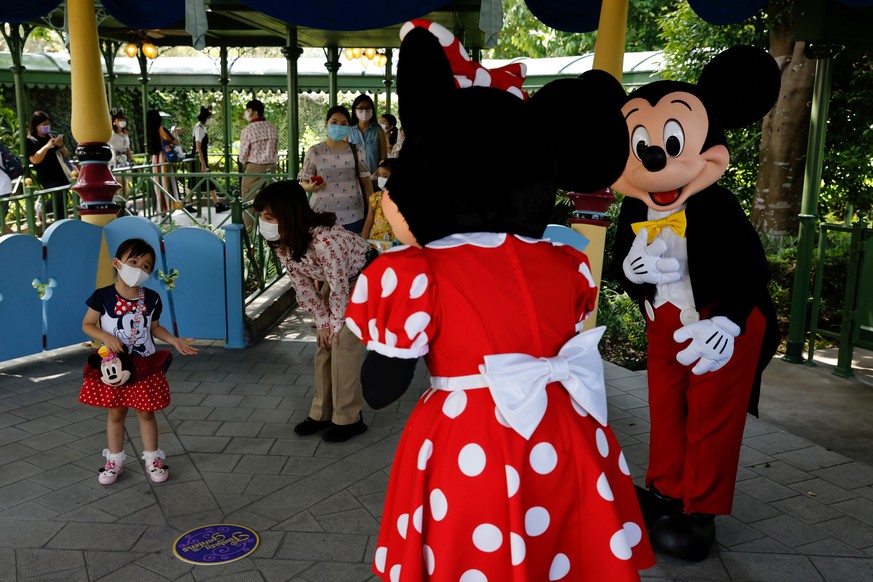 A child greets Disney characters Mickey Mouse and Minnie Mouse during the reopening day of Disneyland to the public, after a second closure due to the coronavirus disease (COVID-19) outbreak, in Hong  ...