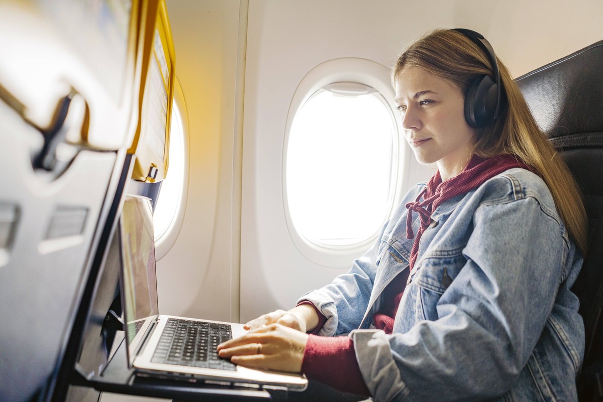 Young woman using laptop and listening music in airplane model released, Symbolfoto, JJF00882