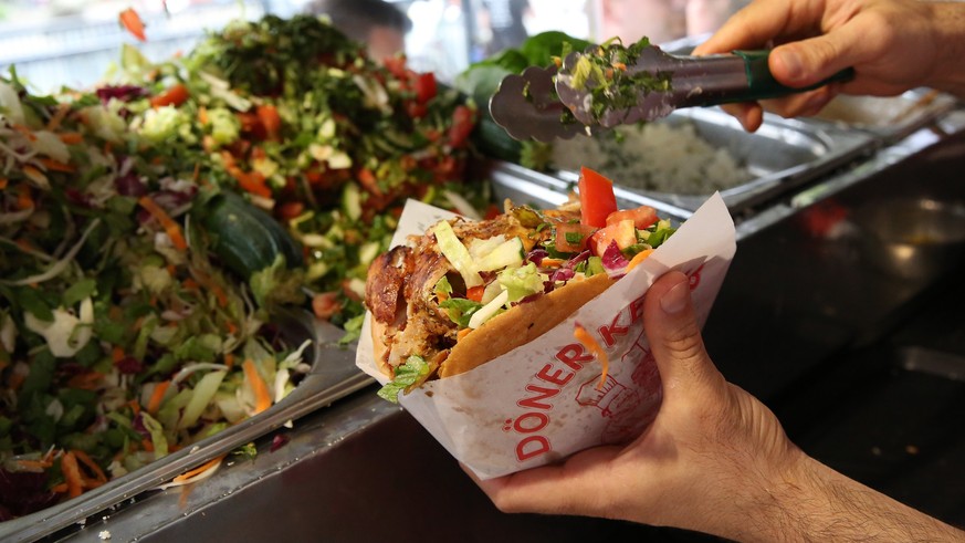 BERLIN, GERMANY - JULY 06: An employee prepares a customer&#039;s order at Mustafas Gemüse Kebap on July 06, 2022 in Berlin, Germany. The döner kebab, a fast food sandwich made of stacked, seasoned me ...