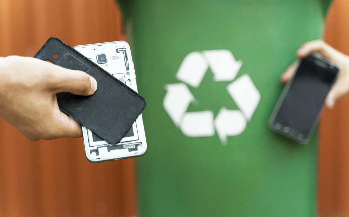 E waste , recycle concept , disassembled smartphone and recycle bin in background
