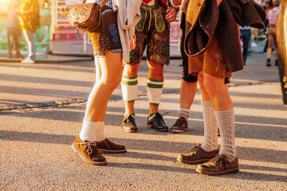 A group of People at beer festival in Munich, Germany. The woman wearing typical dirndl and the men lederhosen - the traditional bavarian clothing.