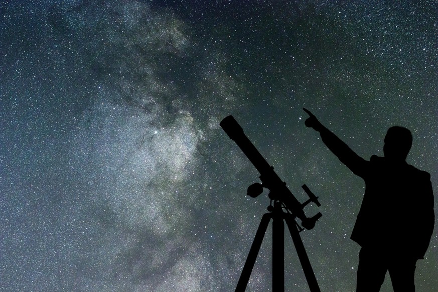 Milky Way. Night sky with stars and silhouette of a standing man with telescope.