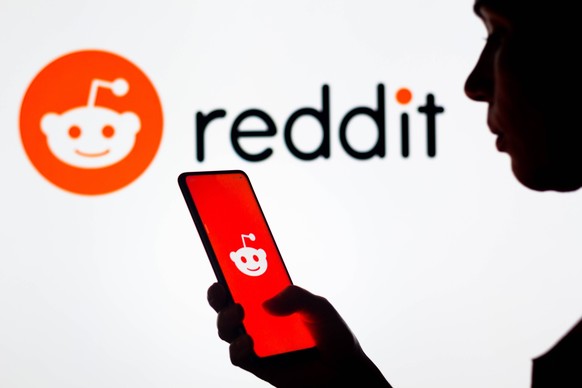 March 28, 2022, Brazil. In this photo illustration, a woman s silhouette holds a smartphone with the Reddit logo displayed on the screen and in the background. March 28, 2022, Brazil. In this photo il ...
