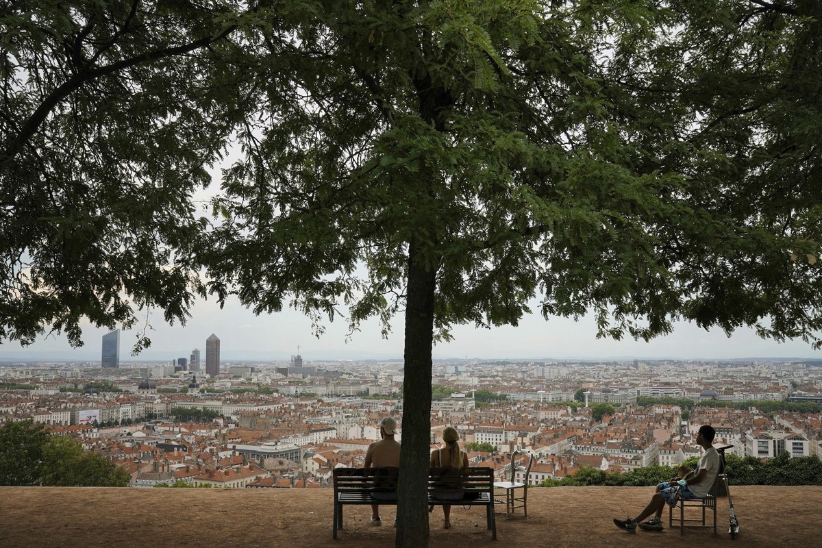 ARCHIV - 09.08.2020, Frankreich, Lyon: Menschen sitzen im franz�sischen Lyon in einem Park auf einer Bank unter einem�Baum und schauen �ber die Stadt. Angesichts einer Hitzewelle bietet Frankreichs dr ...