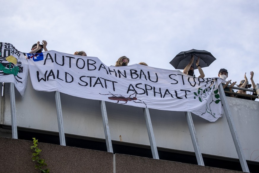 07.07.2023, Hessen, Frankfurt/Main: Klimaaktivisten stehen auf einem Parkhaus im Stadtteil Sachsenhausen hinter einem Banner mit der Aufschrift &quot;Autobahnbau stoppen - Wald statt Asphalt&quot;. In ...