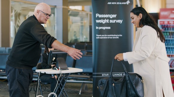In this photo provided by Air New Zealand, a woman hands her bag to a staff member to be weighed ahead of a flight in Auckland, New Zealand, on May 29, 2023. New Zealand&#039;s national airline is ask ...