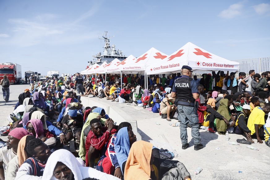 15.09.2023, Italien, Lampedusa: Migranten warten darauf, von der Insel Lampedusa auf das Festland gebracht zu werden. Die Ankunft Tausender Bootsmigranten innerhalb weniger Tage bringt die italienisch ...