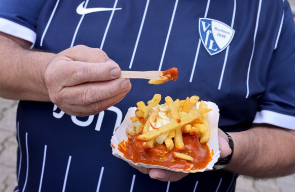BOCHUM, GERMANY - AUGUST 06: A fan of Bochum eats curry sausage with chips during the Bundesliga match between VfL Bochum 1848 and 1. FSV Mainz 05 at Vonovia Ruhrstadion on August 06, 2022 in Bochum,  ...