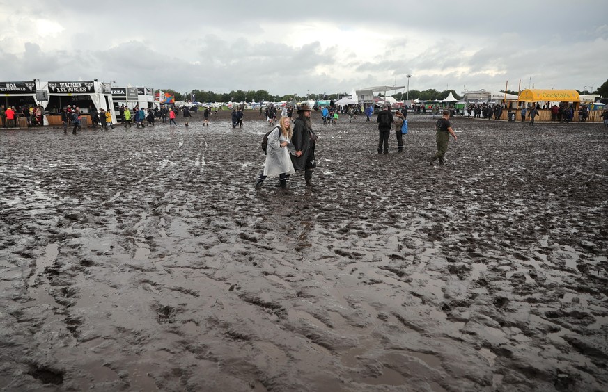 01.08.2023, Schleswig-Holstein, Wacken: Metal-Fans sind auf dem schlammigen Festivalgelände unterwegs. Das Wacken Open-Air (WOA) vom 2. bis 5. August gilt als größtes Heavy-Metal-Festival der Welt und ...