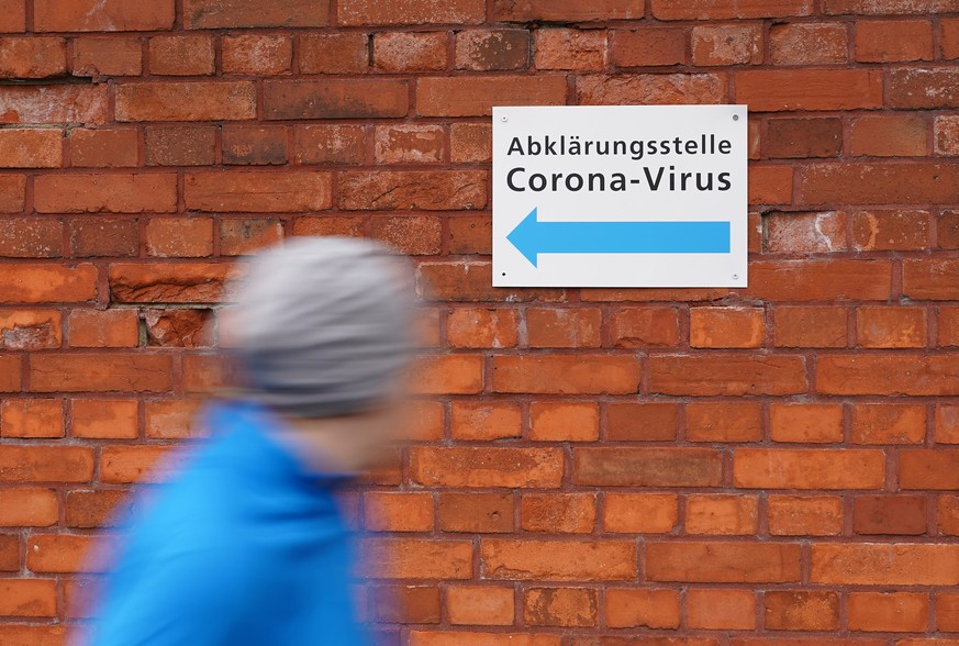 BERLIN, GERMANY - MARCH 09: A woman jogs past a sign pointing in the direction of the facility where visitors seeking to take a test for possible coronavirus infection can go at the Vivantes Wenckebac ...