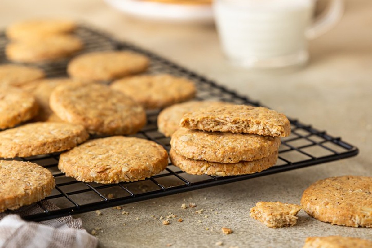 Healthy oatmeal cookies with cereals, seeds and nuts with a cup of milk on concrete background. Diet vegan cookies. Selective focus.