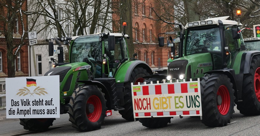 08.01.2024, Schleswig-Holstein, Kiel: Landwirte demonstrieren mit ihren Treckern vor dem Landtag und haben Plakate mit der Aufschrift &quot;Das Volk steht auf&quot; und &quot;Noch gibt es uns&quot; an ...