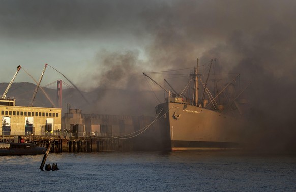The Liberty ship SS Jeremiah O&#039;Brien appears through the clearing smoke of a four-alarm fire burning on Pier 45 in San Francisco on Saturday, May 23, 2020. (Karl Mondon/Bay Area News Group/TNS) P ...