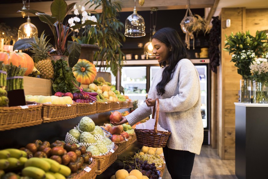 Young woman carrying wicker basket while buying fruits in grocery store model released Symbolfoto property released ABZF03176