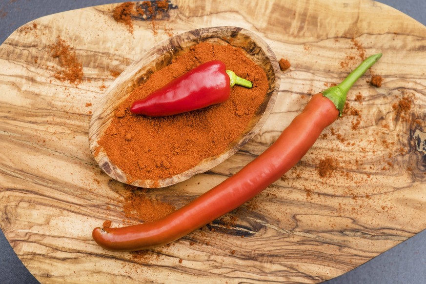 Chilischoten und Paprikapulver auf einem Holzbrett chilicote and paprika powder on a wooden board BLWS710534 *** Chillies and Paprika powder at a Wooden board chilicote and Peppers Powder ON a Wooden  ...