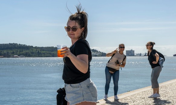 LISBON, PORTUGAL - APRIL 13: Irish tourist Rebekah and friends pose for picture by the Tagus River near MAAT museum in Belem, an area most favored by tourists, on April 13, 2023 in Lisbon, Portugal. R ...