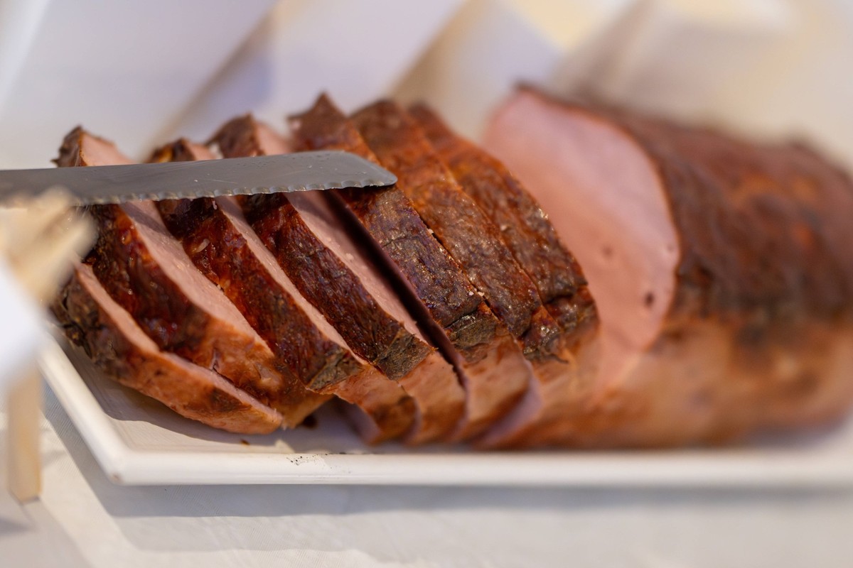 Frisch aufgeschnittene Leberkäse Fleischkäse Scheiben serviert , Deutschland, 28.12.2024, Aufgeschnittener Leberkäse Fleischkäse auf einem Teller, mit einem Messer arrangiert ein herzhaftes Gericht fü ...