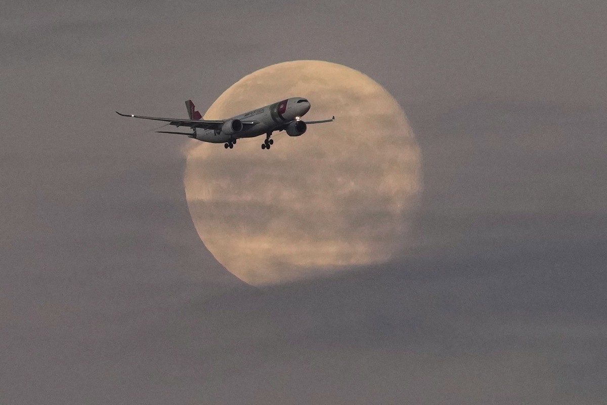 14.05.2025, Portugal, Lissabon: Ein Flugzeug der TAP Air Portugal nähert sich vor Sonnenaufgang dem Flughafen von Lissabon, während der Mond noch am Himmel steht. Foto: Armando Franca/AP/dpa +++ dpa-B ...
