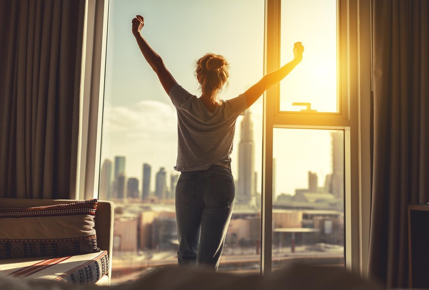 Frau steht morgens am Fenster