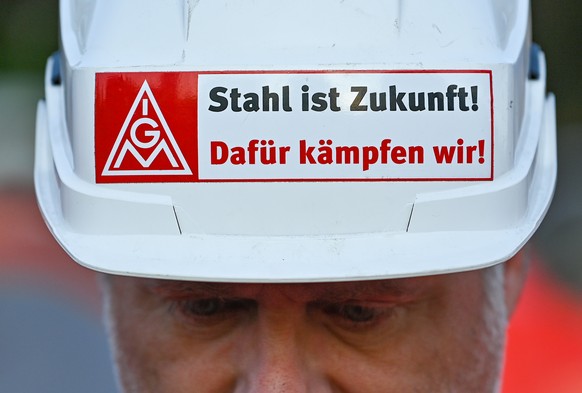 02 June 2022, Brandenburg, Eisenhüttenstadt: During a warning strike, a steel worker from ArcelorMittal Eisenhüttenstadt GmbH wears a protective helmet with the inscription 