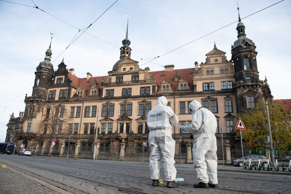 ARCHIV - 25.11.2019, Sachsen, Dresden: Zwei Mitarbeiter der Spurensicherung stehen vor dem Residenzschloss mit dem Gr