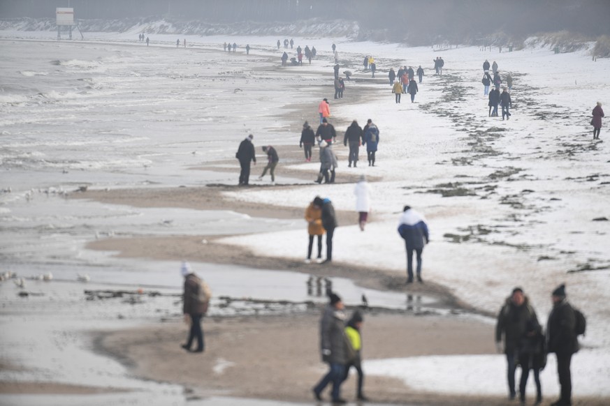 Januar 2021: Spaziergänger gehen am leicht verschneiten Strand der Insel Usedom.