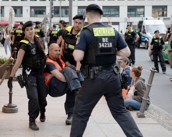 Polizist:innen tragen einen Aktivisten fort.