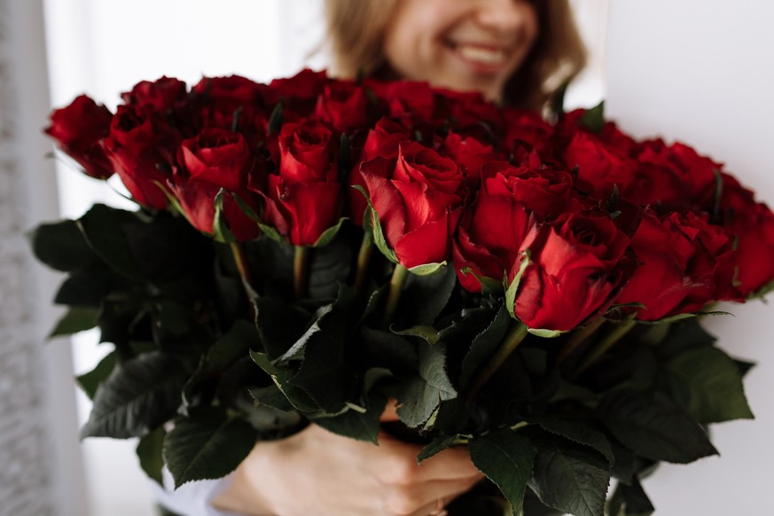 Happy Valentine&#039;s Day. smiling young woman holding a big luxury bouquet of red roses flowers. Celebration of engagement or wedding. Birthday gift