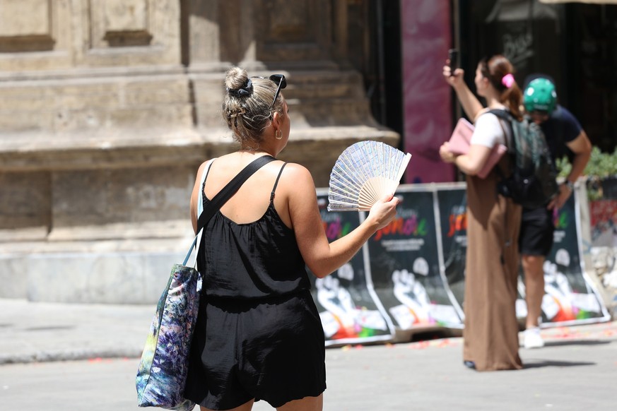 16.07.2023, Italien, Palermo: Eine Frau benutzt ihren Fächer während der Hitze. Temperaturen um die 40 Grad tagsüber und 30 Grad nachts machen den Menschen in weiten Teilen Südeuropas zu schaffen. Fot ...