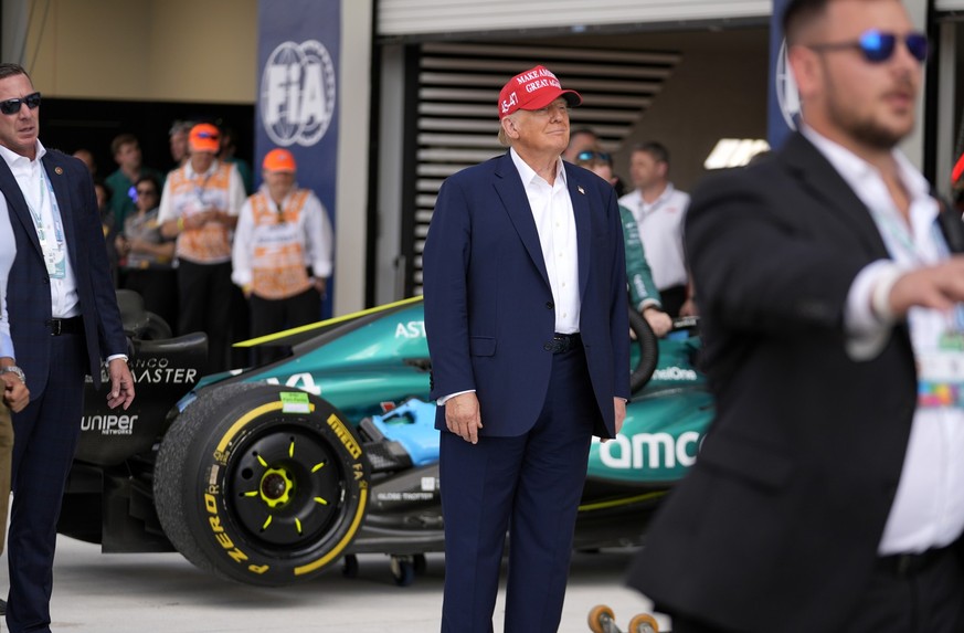 Republican presidential candidate former President Donald Trump, center, walks along the pit road after the Miami Formula One Grand Prix auto race, Sunday, May 5, 2024, in Miami Gardens, Fla. (AP Phot ...