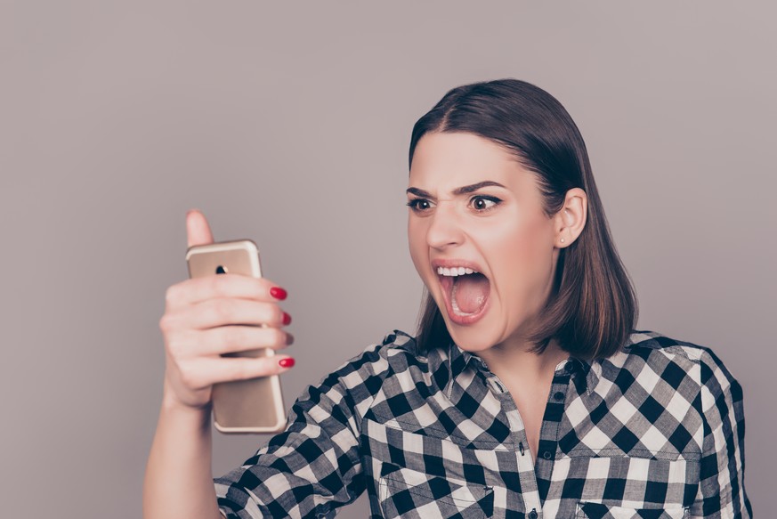 A portrait of an angry young woman disappointed with the news from her work and screaming on the phone