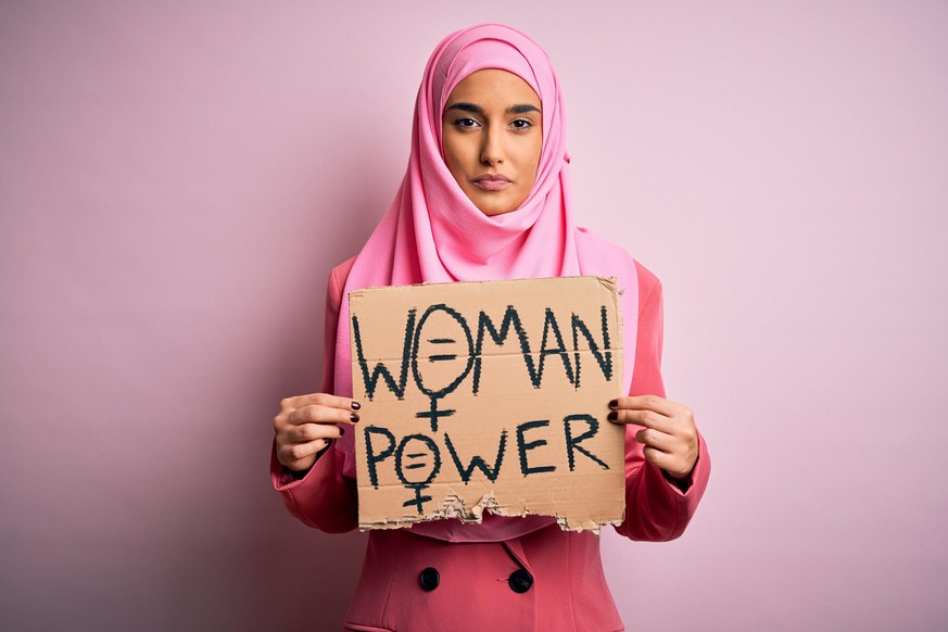 Young activist arab woman wearing pink muslim hijab holding banner with power message with a confident expression on smart face thinking serious