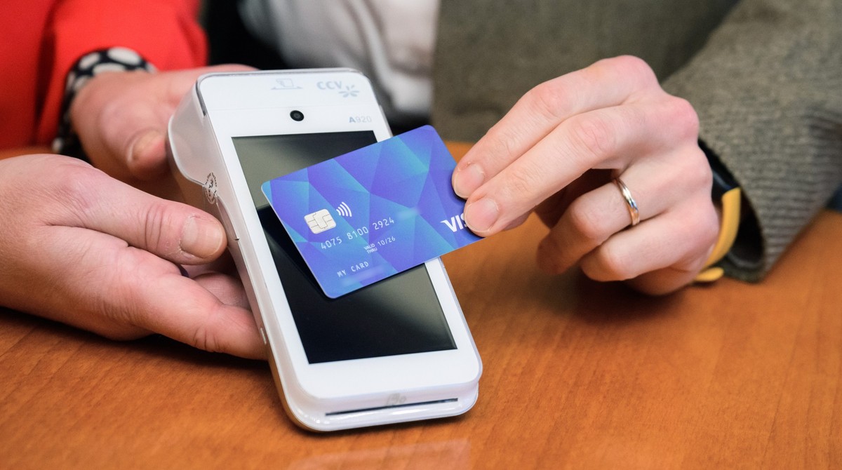 ARCHIV - 08.12.2023, Niedersachsen, Hannover: Eine VISA-Debit Karte wird bei einer Pressekonferenz im Rathaus Hannover vor ein Leseger�t gehalten. Fl�chtlinge ohne deutsches Bankkonto erhalten in Hann ...