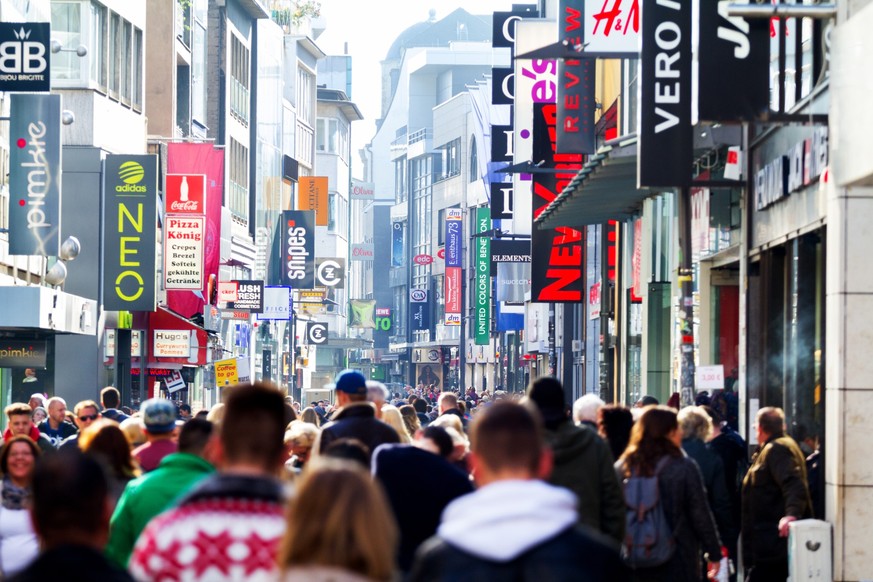 Autumn sales daytime scene with crowd of people in pedestrian zone Hohe Straße in Cologne. View along street over crowd. At facades are many banners of many stores. Non editorial crowd shot wothout re ...