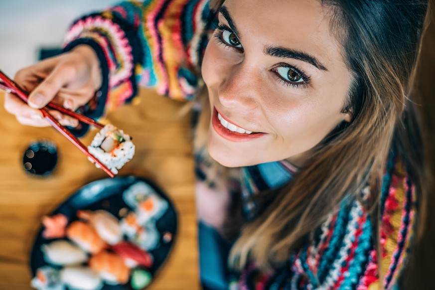 Top view Crop woman eating sushi