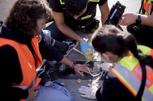 Police officers remove the glued hand of a climate activist from a road during a climate protest in Berlin, Germany, Monday, Sept. 18, 2023. Activists of the &quot;Last Generation&quot;, Letzte Genera ...