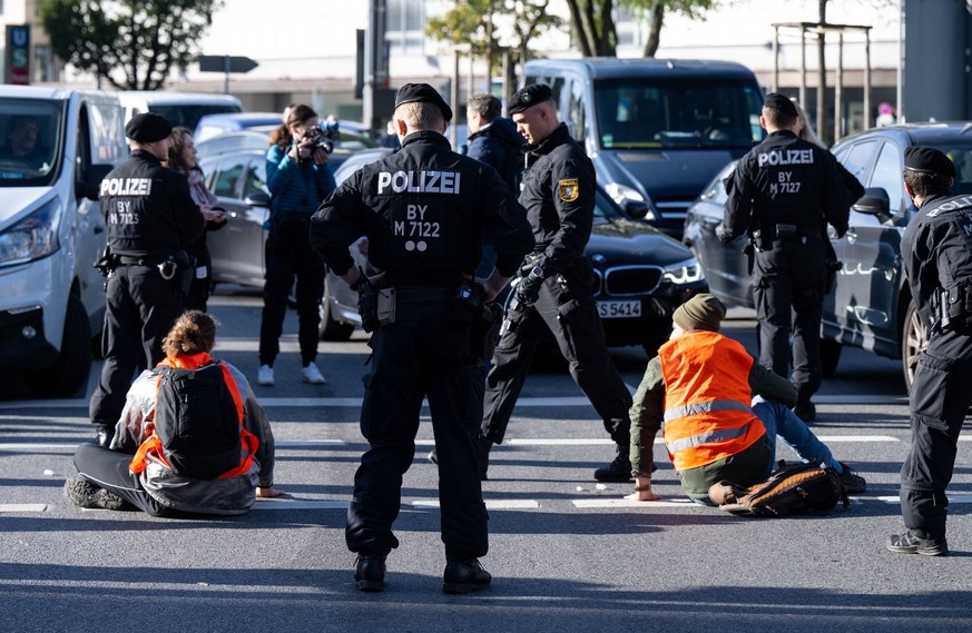 07.11.2022, Bayern, München: Polizeibeamte stehen neben Klimaaktivisten, die sich am Karlsplatz in der Innenstadt auf die Fahrbahn geklebt und somit die Straße blockiert haben. Foto: Sven Hoppe/dpa ++ ...